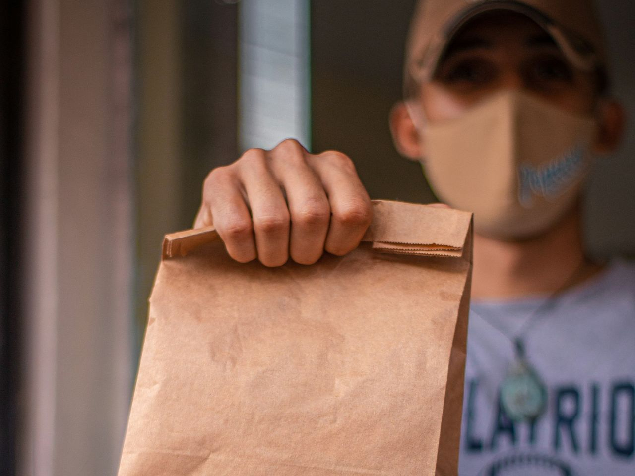 A man wearing a face mask holding a brown bag